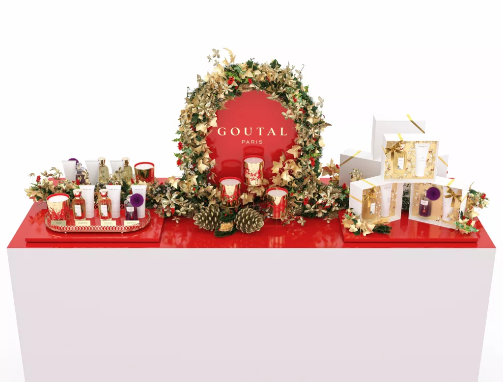 Présentoir 3D retail Goutal Noël avec fronton arrondi, couronne de lierre doré, pommes de pin, bougies, boîtes cadeaux et plateau produit doré.